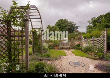 Summer plants, mosaic artwork, trellis screen, arbour archway & seat - beautiful, traditional, landscaped, designed garden - Yorkshire, England, UK.