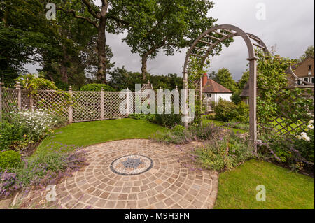 Plants, mosaic artwork, trellis screen & arbour archway in summer - beautiful, traditional, landscaped, designed garden - West Yorkshire, England, UK. Stock Photo