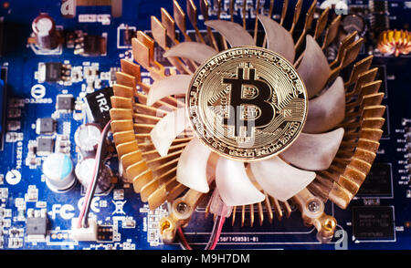 Physical Gold Bitcoin Coin on a computer video card. New independent worldwide cryptocurrency. Stock Photo