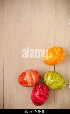 Four colored Easter eggs on a bright wooden taxture Stock Photo