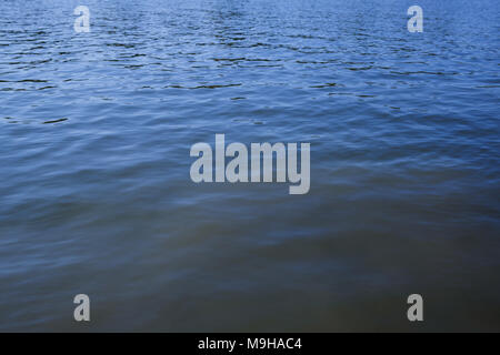 Water surface with ripples and sunrays reflections Stock Photo