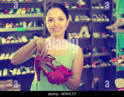 Beautiful woman customer is showing modern heeled sandals that she bought in shoes shop Stock Photo