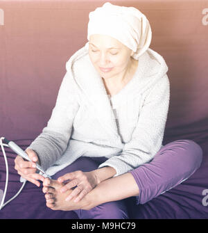 Senior woman starting feet pedicuring with special devices at home Stock Photo