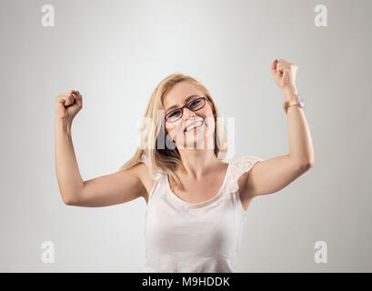 Portrait of happy woman exults pumping fists ecstatic celebrates success against gray background. Stock Photo