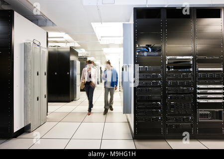 Computer server room racks with technician in background. Stock Photo
