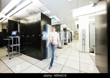 Computer server room racks with technician in background. Stock Photo