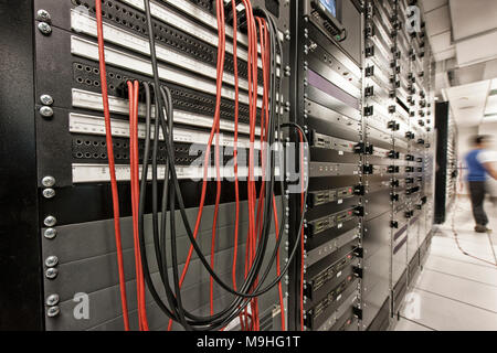 Computer server room racks with technician in background. Stock Photo