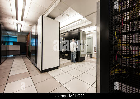 Computer server room racks with technician in background. Stock Photo
