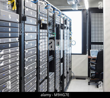 Servers in an aisle of racks in a computer server farm. Stock Photo