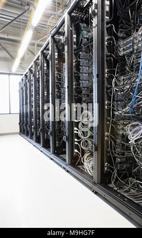 Servers in an aisle of racks in a computer server farm. Stock Photo