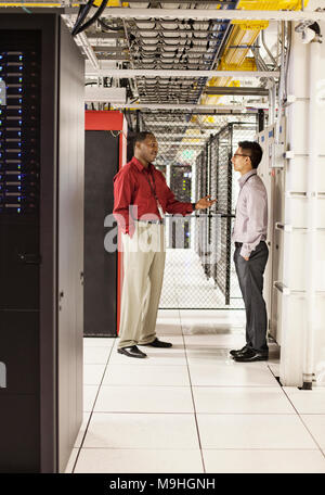 Computer technicians discussion an issue in a large computer server farm. Stock Photo