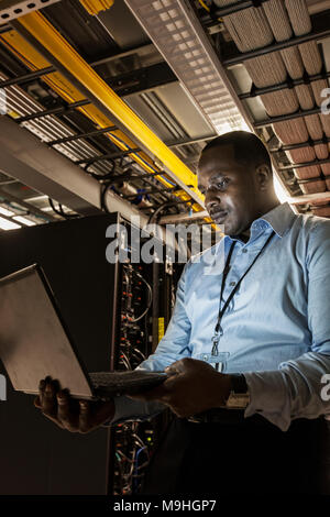 Black man technician doing diagnostic tests  on computer servers in server farm. Stock Photo