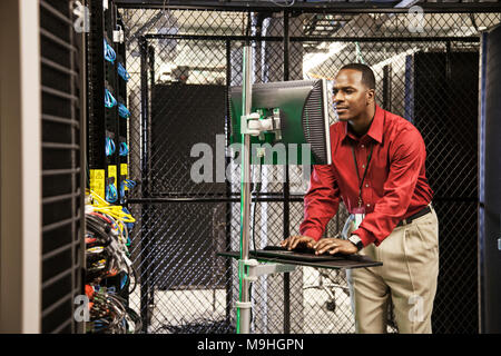 Black man technician doing diagnostic tests  on computer servers in server farm. Stock Photo