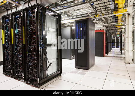Racks of servers aligned in rows in a large computer server farm. Stock Photo