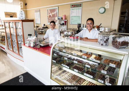 Portrait of Caucasian women co-owners of a candy shop standing behind counter. Stock Photo