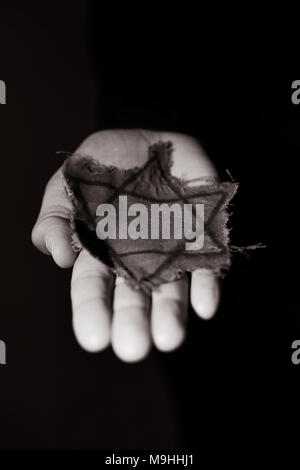 closeup of a ragged Jewish badge in the hand of a man, with a dramatic effect Stock Photo