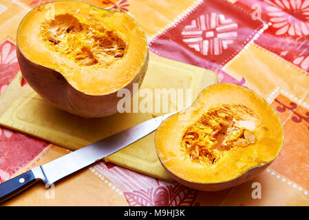 Two halves of a pumpkin on the table and a kitchen knife Stock Photo
