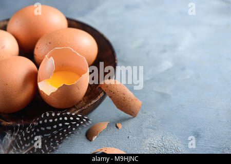 Yolk in an eggshell close-up. Raw cooking ingredients background with copy space. Modern Easter concept with brown hen eggs Stock Photo