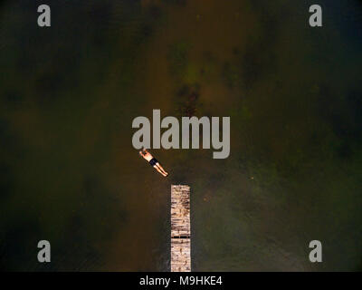 A tourist jumps of a pier into a lake in Zimbabwe's little Connemara, Nyanga. Stock Photo