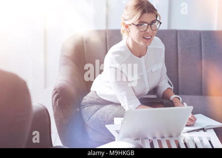 Joyful nice businesswoman sitting on the sofa Stock Photo
