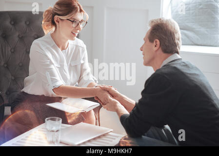 Nice delighted man holding the hand of his psychologist Stock Photo