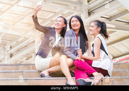 Businesswoman sitting and using smartphone to take selfie with colleague together Stock Photo