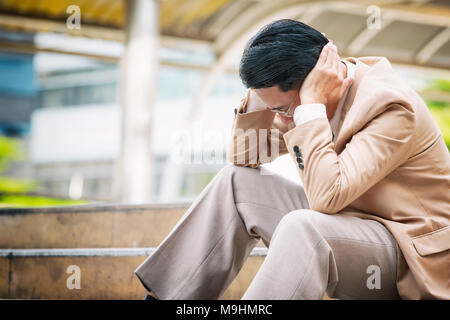 Closeup of stressed Asian businessman to touch his head feeling bad and headache Stock Photo