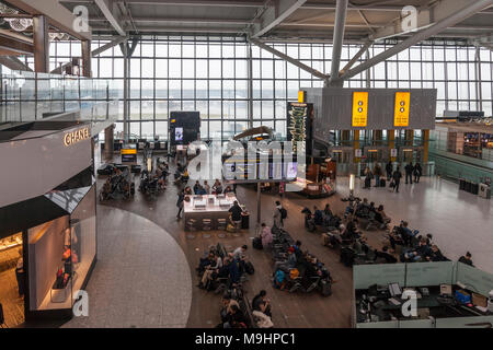 Air travellers waiting in the departures area of Heathrow Airport, Terminal Five. Sitting area, phone charging stations, Caviar House, Chanel, people, Stock Photo