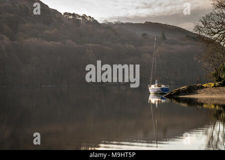 A lone yaught moored by the shore on Coniston Water in the Lake District. Stock Photo