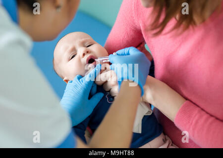 Baby on mothers hand at hospital. Nurse making infant oral vaccination against rotavirus infection. Children health care and disease prevention Stock Photo