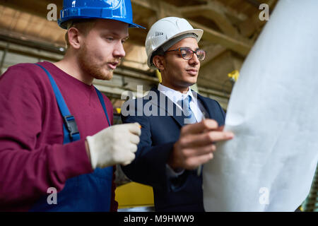 Engineers Discussing Blueprints Stock Photo