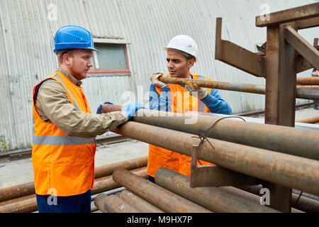 Workers Moving Pipes Stock Photo