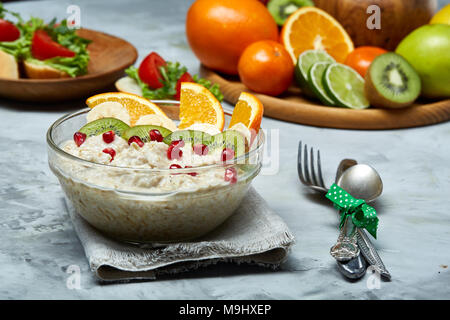 Breakfast still life with oatmeal porridge and fruits served with fork, spoon on homespun napkin over wooden background, top view, selective focus, sh Stock Photo