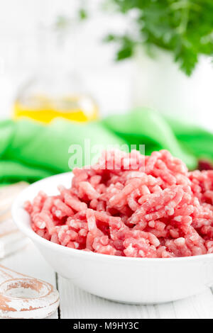 Forcemeat. Raw ground pork meat in bowl on white kitchen table. Fresh minced meat Stock Photo