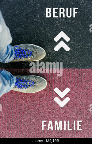Reaching a crossroads having to choose between beruf and familie meaning job and family symbolized by two feet standing on two different colors with a Stock Photo
