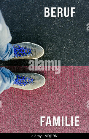 Reaching a crossroads having to choose between beruf and familie meaning job and family symbolized by two feet standing on two different colors with a Stock Photo