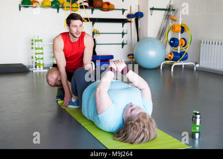 Obese Woman Doing Crunches in Health Club Stock Photo