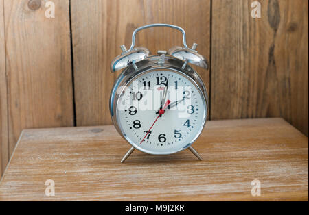 An old fashioned silver coloured bed side analogue pre digital alarm clock Stock Photo