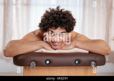 Handsome man lying down on massage table and waiting for healthy massage in spa center. Stock Photo