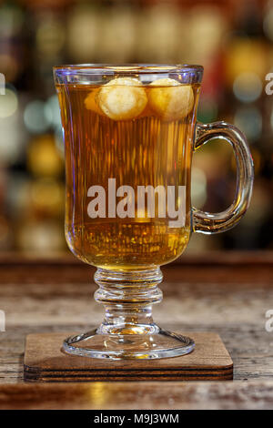 Spicy alcoholic drink with whiskey in a glass, garnished with apple, on the bar in the restaurant, space for text Stock Photo