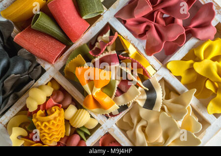 Mixed set of dry multi-colored Italian pasta on a white old wooden box. Background. Stock Photo