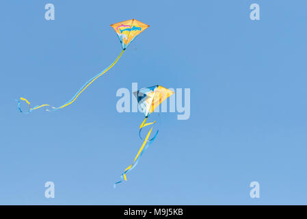 Two colourful kites flying against a blue cloudless sky. Stock Photo