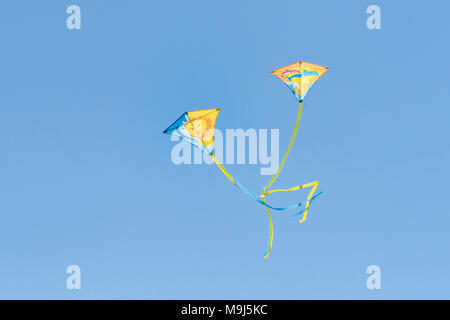 Two colourful kites flying against a blue cloudless sky. Stock Photo