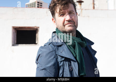 portrait of 45 year old man with blue jacket and mobile in his hand Stock Photo