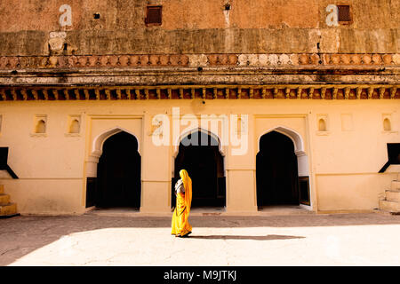 A woman walking past archways in the Amer Fort. Stock Photo