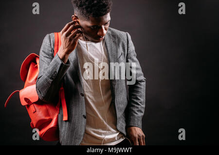 close up cropped shot of Afro guy with pink backpack putting on earphones. enjoy music. music lover Stock Photo