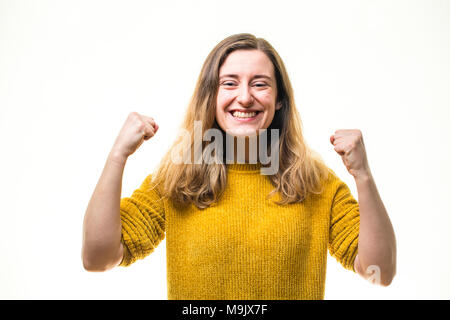 Celebrating success - A happy smiling positive enthusiastic  young Caucasian woman girl , pumping her fists in exuberance, full of passion and committment  - UK Stock Photo