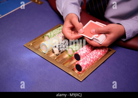 Close up of holdem dealer with playing cards and chips on blue table Stock Photo
