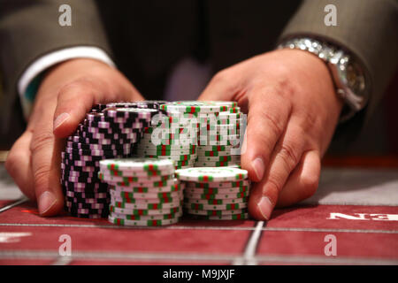 Player at gambling table pusing large stack of chips Stock Photo