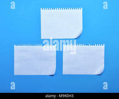three blank sheet of paper with curved corners on a blue background, the sheets into the cell and taken out from a notebook Stock Photo